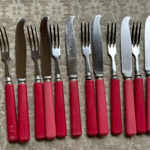 Op de afbeelding: Set van tien zilverkleurig bestek met rode kunststof handvatten. De set bevat vijf vorken en vijf botermesjes.