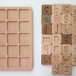 May include: Wooden alphabet learning set. The set includes a light-colored wooden tray with 16 square indentations and 26 wooden letter tiles. The tiles are engraved with lowercase letters. Some tiles are a darker wood color.