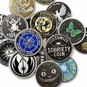 May include: A collection of circular metal sobriety coins featuring various designs, including a blue compass, a green butterfly, a dog portrait, a grinning cat face, and text such as Customize Your Own Sobriety Coin, Two Years, and Duck Hunt.