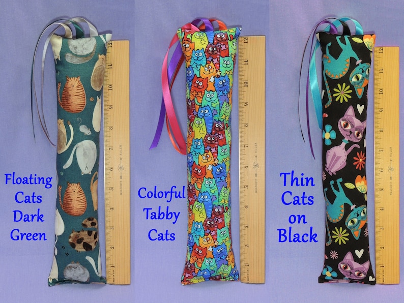 May include: Three cat toy tubes with cat patterns. The first is dark green with floating cats, the second is a colorful tabby cat pattern, and the third is black with thin cats. Each tube is about 30 cm long.