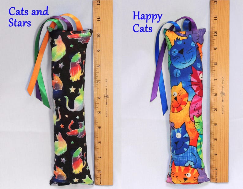 May include: Two catnip toys with colorful cat designs. The first toy is black with rainbow cats and stars and the text "Cats and Stars". The second toy is blue with colorful cats and the text "Happy Cats".