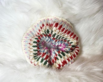 May include: A colorful knitted hair scrunchie with a white background and red, green, blue, and pink stripes.