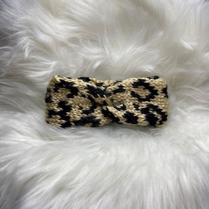 Puede incluir: Una diadema de tejido de punto con estampado de leopardo negro y marrón.
