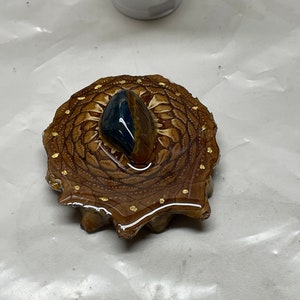 Peut inclure: Un plateau en résine avec un motif de mandala brun et or et une pierre précieuse bleue et brune au centre.