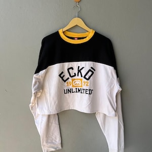 May include: White, black, and yellow long-sleeved cropped sweatshirt with the text "ECKO 1972 UNLIMITED" on the front.