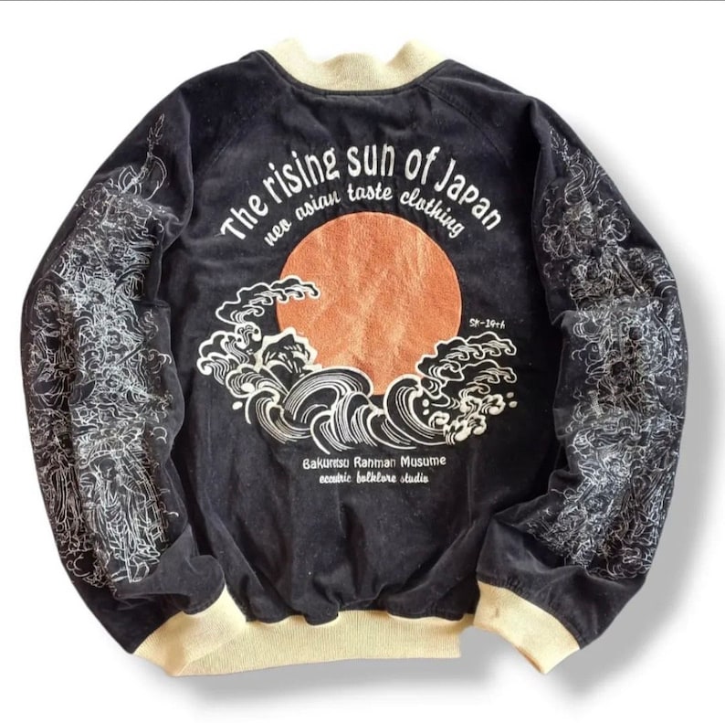 Puede incluir: Chaqueta bomber de terciopelo negro con un dise&ntilde;o bordado en blanco de un sol naciente y olas. El texto "The rising sun of Japan neo asian taste clothing" est&aacute; bordado en la parte posterior. El texto "Bakunitsu Rahman Musume eccentric folklore studio" est&aacute; bordado debajo del dise&ntilde;o. El texto "S-1916" est&aacute; bordado en el lado derecho del dise&ntilde;o.