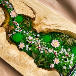 Op de afbeelding: Een rechthoekig houten dienblad met een riviersc&egrave;ne. De rivier is gevuld met groen mos, kleine rotsen en miniatuur koi-vissen. Roze bloemen en waterlelies zijn ook aanwezig. De randen van de lade zijn van natuurlijk hout.