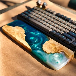 May include: A wooden keyboard wrist rest with a blue and white epoxy resin inlay. The resin has a swirling pattern, resembling water.