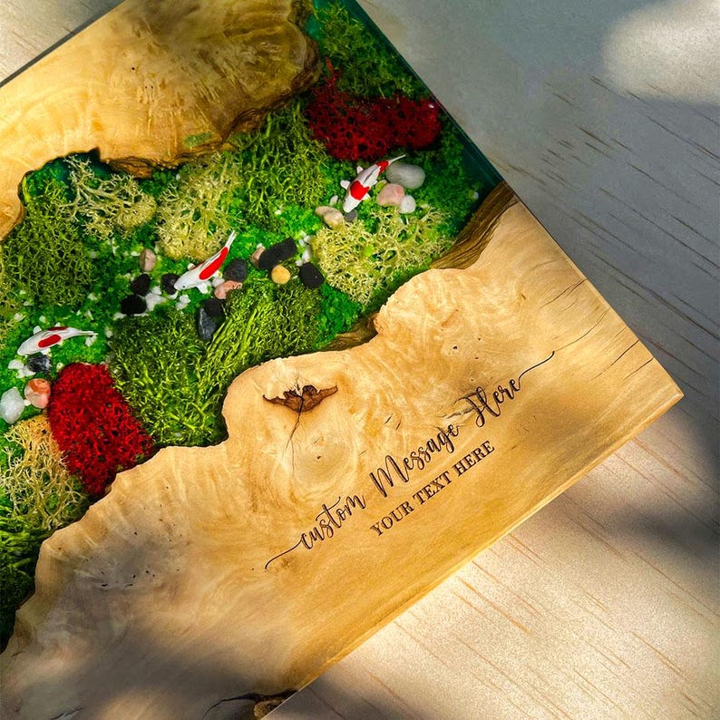 May include: A wooden decorative piece with a live edge design. The piece features a vibrant green moss landscape with miniature koi fish and red accents. The text "custom message here" is engraved on the wood.