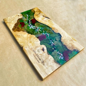 May include: A rectangular wooden art piece with a river-like design. The river is filled with green moss, red accents, and small white and gray stones. The wood has a light brown color with a unique grain pattern. The text "custom Message Here" is visible.