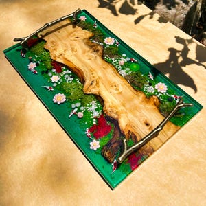 May include: A rectangular serving tray with a green resin base, featuring a natural wood centerpiece. The tray is decorated with miniature koi fish, moss, flowers, and small stones. It has bronze-colored branch handles.