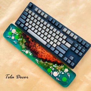 May include: A black mechanical keyboard with gray and black keycaps rests above a decorative wrist rest. The wrist rest features a teal resin design with a wood grain center, koi fish, and floral accents. The text "Tela Decor" is visible.