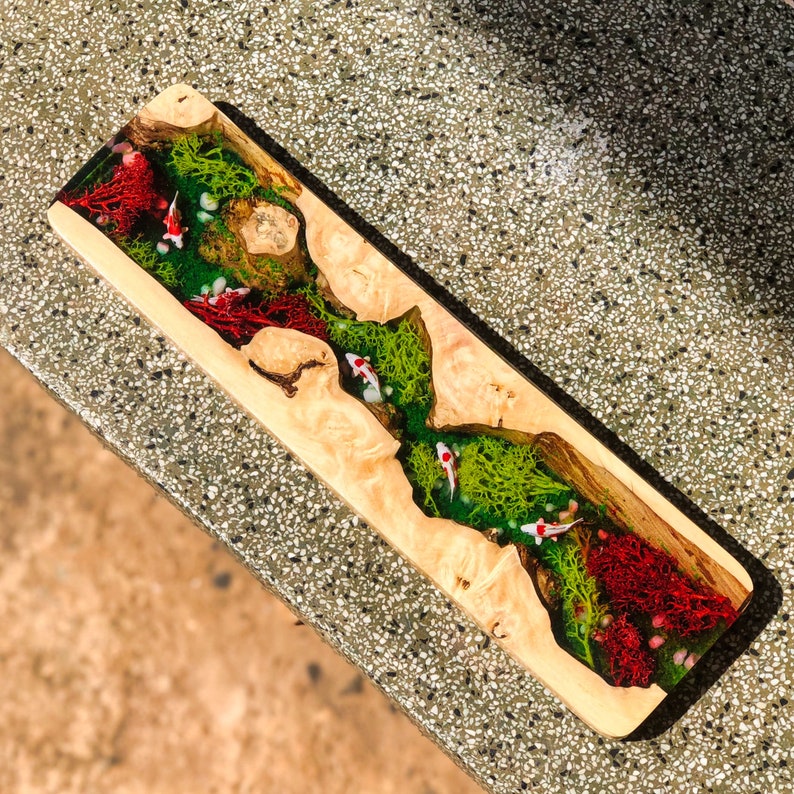 May include: A wooden serving tray with a clear resin inlay featuring green moss, red coral, and white fish. The tray is perfect for serving appetizers, snacks, or desserts.