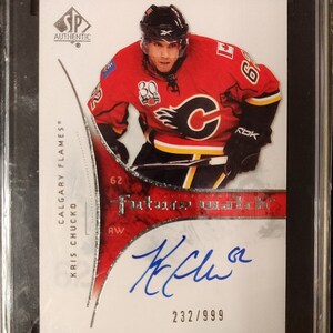 Puede incluir: Una tarjeta de hockey con Kris Chucko de los Calgary Flames. La tarjeta es una SP Authentic Rookie Auto 2009-10 numerada 232/999. La tarjeta está calificada 98 Gem Mint 10 por SGC.