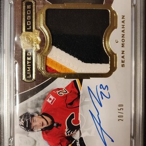 May include: A graded hockey card featuring Sean Monahan of the Calgary Flames. The card is a 2014 Upper Deck The Cup Limited Logos Autographed card, numbered 20/50. The card is in a PSA 9 graded holder.