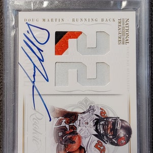 May include: A graded trading card featuring Doug Martin, a running back, with his signature. The card includes a jersey patch with the number 22. The card is encased in a protective holder and has the text "2012 Panini Nat.Treas."