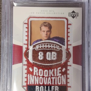May include: A red, white, and black patch with a football graphic and the text "Rookie Innovation Boller" and "Kyle Boller". The patch is framed in a clear plastic case with a Beckett grading label.
