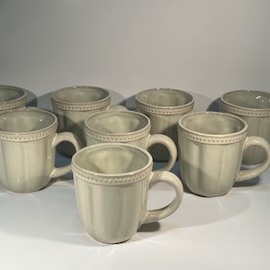 May include: Set of eight light gray ceramic mugs with a beaded rim and a fluted design.