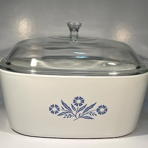 May include: White oval casserole dish with a blue floral design and a clear glass lid.