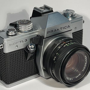 May include: A silver Praktica Super TL3 35mm film camera with a black Pentacon auto 1.8/50 lens.