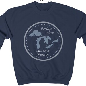 May include: Navy blue sweatshirt with a graphic of the Great Lakes. The graphic says "Always Fresh Sometimes Frozen" with a snowflake in the word "Frozen".