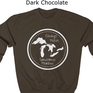 May include: Dark chocolate sweatshirt with a white graphic of the Great Lakes. The graphic says "Always Fresh Sometimes Frozen" with a snowflake.