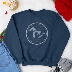 May include: A navy blue sweatshirt with a gray circle graphic featuring a map of the Great Lakes and the text "Always Fresh, Sometimes Frozen".
