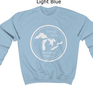 May include: Light blue sweatshirt with a white graphic of the Great Lakes. The graphic says "Always Fresh Sometimes Frozen" with a snowflake symbol.