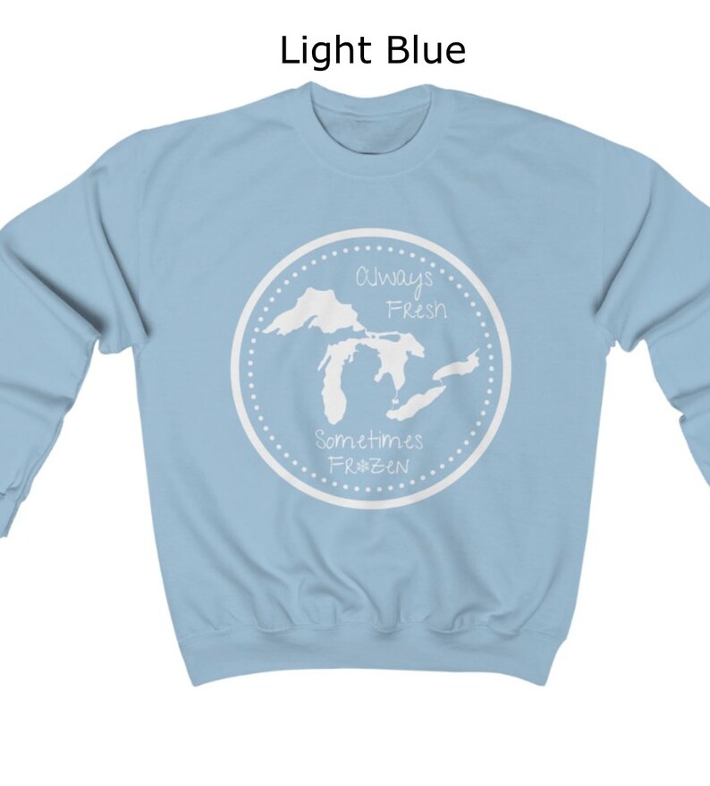 May include: Light blue sweatshirt with a white graphic of the Great Lakes. The graphic says "Always Fresh Sometimes Frozen" with a snowflake symbol.