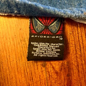 May include: A black Spider-Man label featuring the Spider-Man logo and text. The label states "Spider-Man, the character: TM&&copy;2004 Marvel Characters, Inc. Spider-Man, the movie: &copy;2004 Columbia Pictures Industries, Inc. All rights reserved."