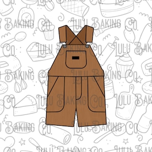 May include: A brown overall cookie cutter with a pocket and suspenders. The cookie cutter is designed in the shape of a pair of overalls. The background features a repeating pattern of baking-related illustrations.