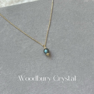 May include: A gold chain necklace with a dark blue oval pendant. The pendant has a subtle shimmer.