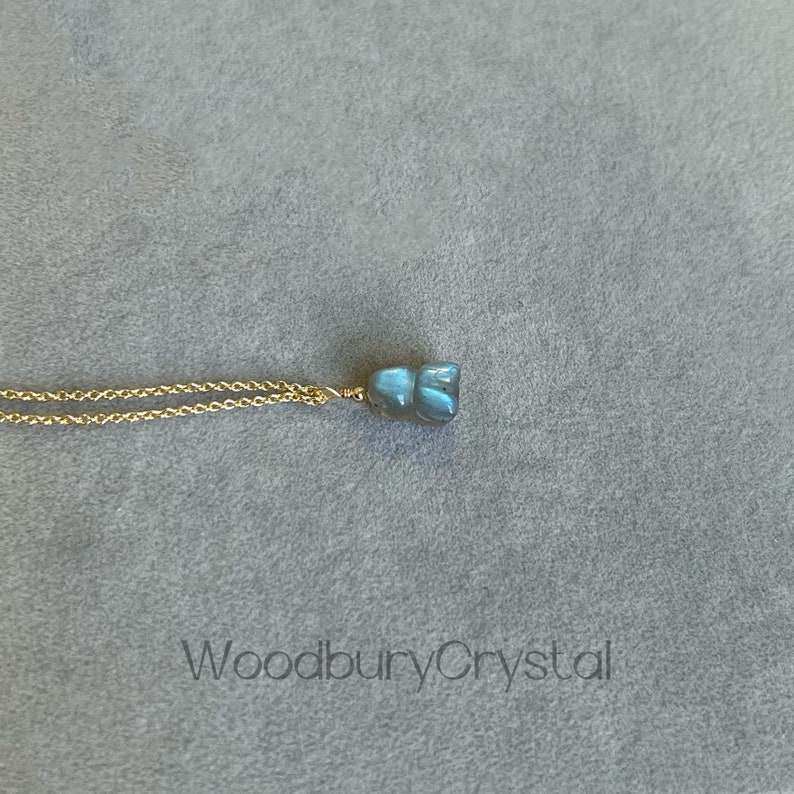 May include: A gold chain necklace with a blue labradorite pendant. The pendant is a raw, irregular shape.
