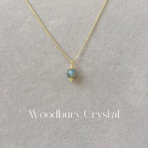 May include: A gold chain necklace with a single round blue labradorite gemstone pendant.