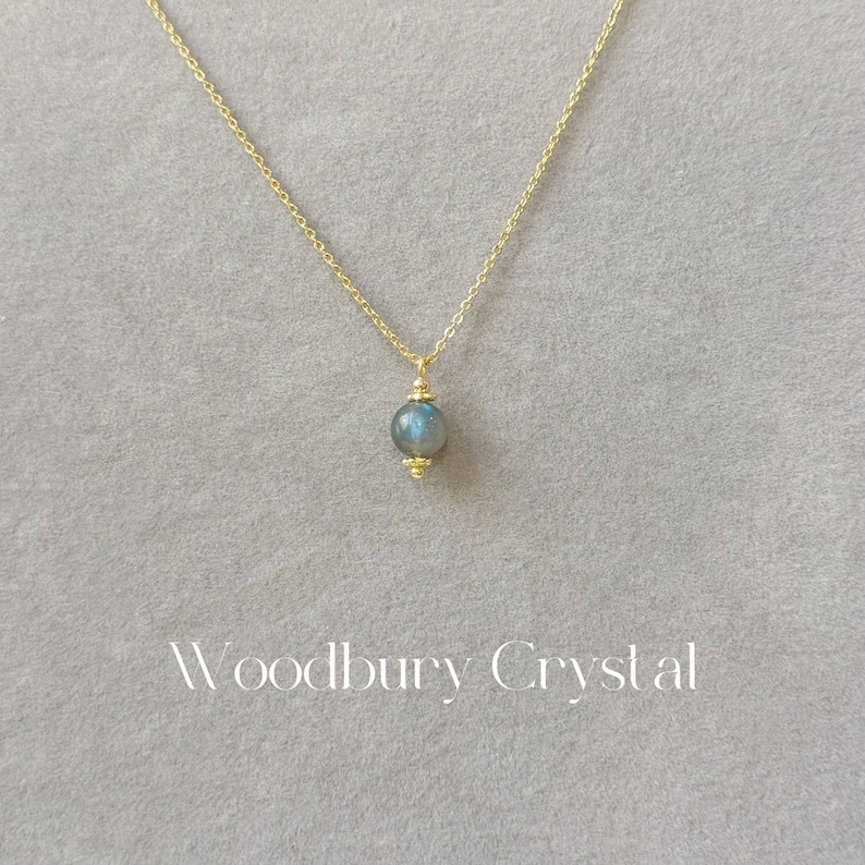 May include: A gold chain necklace with a single round blue labradorite gemstone pendant.