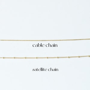 May include: Two gold chains on a white background. The top chain is a cable chain. The bottom chain is a satellite chain.