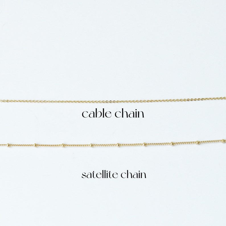May include: Two gold chains on a white background. The top chain is a cable chain. The bottom chain is a satellite chain.