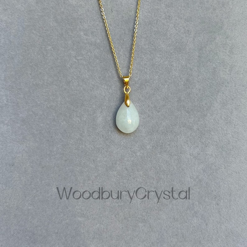 Puede incluir: Un delicado collar de cadena dorada con un colgante en forma de l&aacute;grima hecho de piedra blanca. El colgante est&aacute; engastado en un bisel dorado.