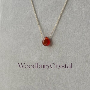 Peut inclure: Un collier d&eacute;licat en cha&icirc;ne dor&eacute;e avec un pendentif en forme de larme en cornaline. Le pendentif est de couleur rouge fonc&eacute; et a une finition lisse et polie. Le collier est simple et &eacute;l&eacute;gant, ce qui en fait un choix parfait pour tous les jours.