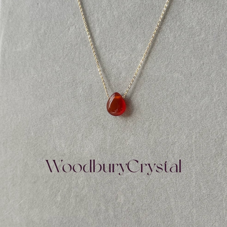 Peut inclure: Un collier d&eacute;licat en cha&icirc;ne dor&eacute;e avec un pendentif en forme de larme en cornaline. Le pendentif est de couleur rouge fonc&eacute; et a une finition lisse et polie. Le collier est simple et &eacute;l&eacute;gant, ce qui en fait un choix parfait pour tous les jours.