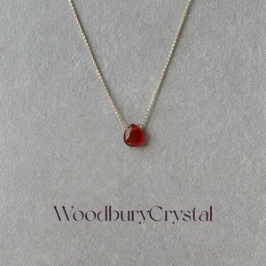 Peut inclure: Un collier d&eacute;licat en cha&icirc;ne dor&eacute;e avec un pendentif en forme de larme en cornaline. Le pendentif est de couleur rouge fonc&eacute;.
