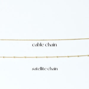 Puede incluir: Dos cadenas de oro sobre un fondo blanco. La cadena superior es una cadena de cable. La cadena inferior es una cadena de sat&eacute;lite.