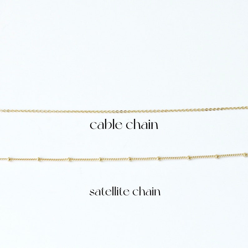 Puede incluir: Dos cadenas de oro sobre un fondo blanco. La cadena superior es una cadena de cable. La cadena inferior es una cadena de sat&eacute;lite.