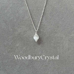May include: A silver chain necklace with a white gemstone pendant. The pendant is a round, faceted bead with a silver bail.