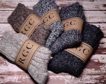 May include: A pile of six pairs of wool socks in various shades of brown, gray, and black. Each pair is wrapped in brown paper with the text "RGC" printed on it.