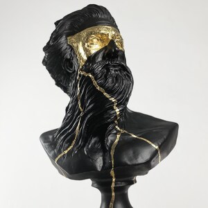 Puede incluir: Busto de escultura de un hombre con barba, negro y dorado. La escultura est&aacute; agrietada y tiene detalles dorados.