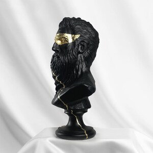 Puede incluir: Busto de escultura de un hombre con barba en negro y dorado. El busto est&aacute; agrietado y tiene detalles dorados.