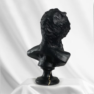 Puede incluir: Busto de escultura en negro y dorado de la cabeza y los hombros de una persona. El busto est&aacute; sobre un pedestal negro con detalles dorados.