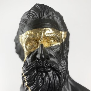 Puede incluir: Busto de escultura de un hombre con barba, negro y dorado. La cara del hombre est&aacute; parcialmente cubierta con pan de oro.