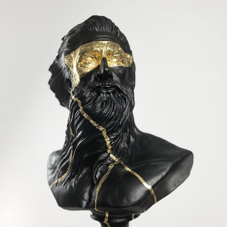 Puede incluir: Busto de escultura negra de un hombre con una larga barba. La escultura est&aacute; decorada con detalles dorados, creando un contraste llamativo.